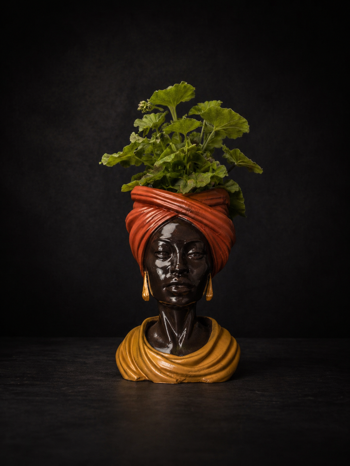 Golden Hour cast stone head planter with green plant on moody black background