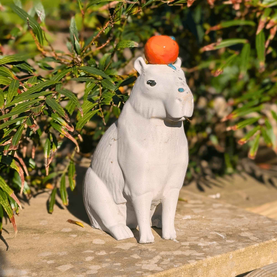 Capybara with orange cast stone sculpture for garden display