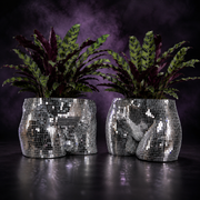 Pair of silver mirror mosaic torso planters with leafy plants on a purple studio backdrop