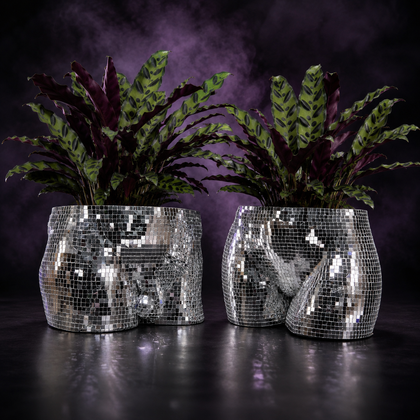 Pair of silver mirror mosaic torso planters with leafy plants on a purple studio backdrop