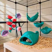 Eight botanical rat cage accessories in teal green, red, purple and pink, with a white rat resting inside the leaf hide.