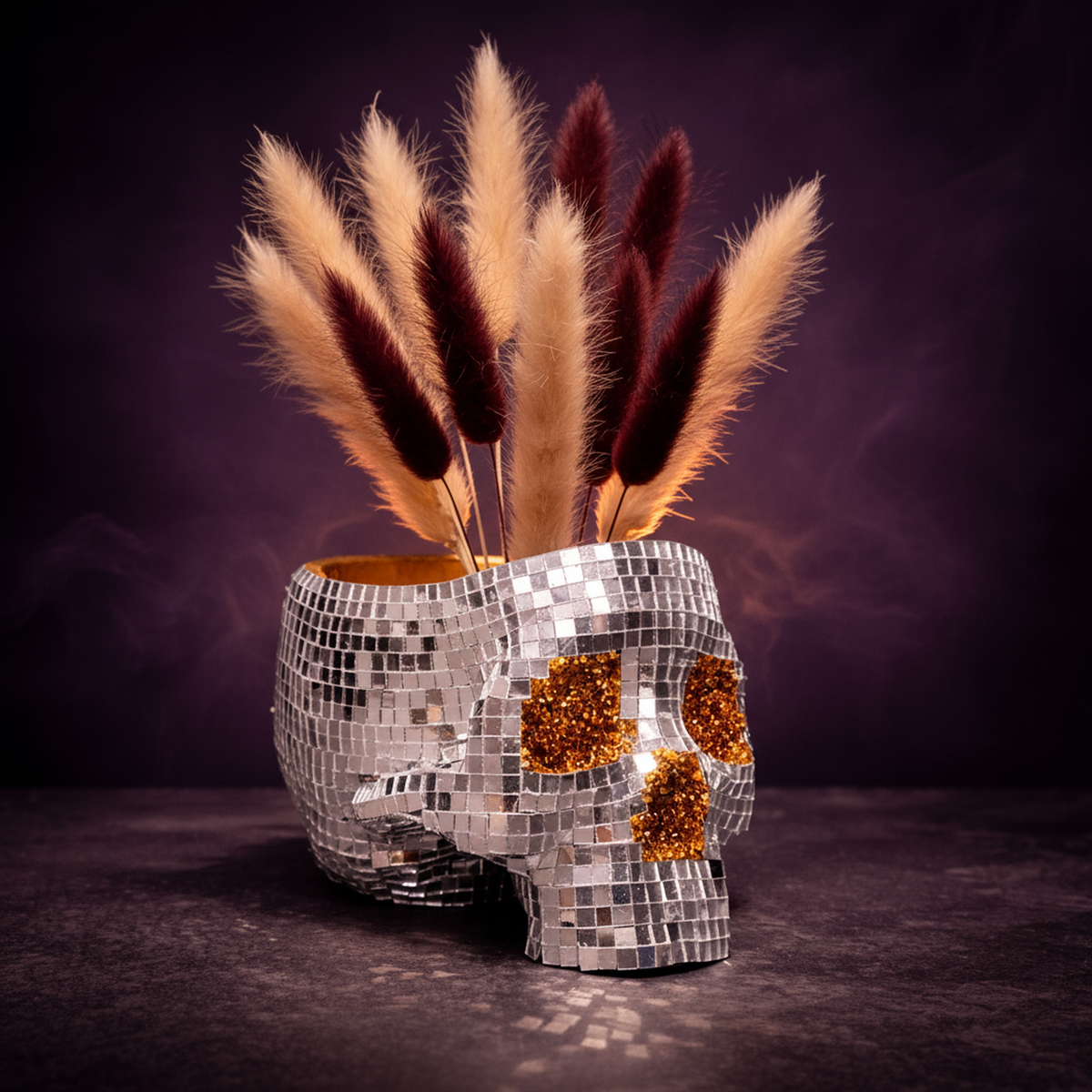 Disco skull planter filled with dried cream and burgundy grasses on a smoky purple backdrop