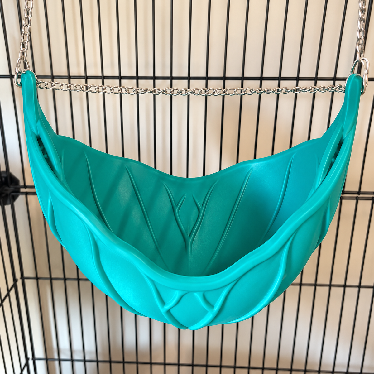 An elevated close view into the empty cupped green leaf hammock, showing its raised veins and hanging chain.