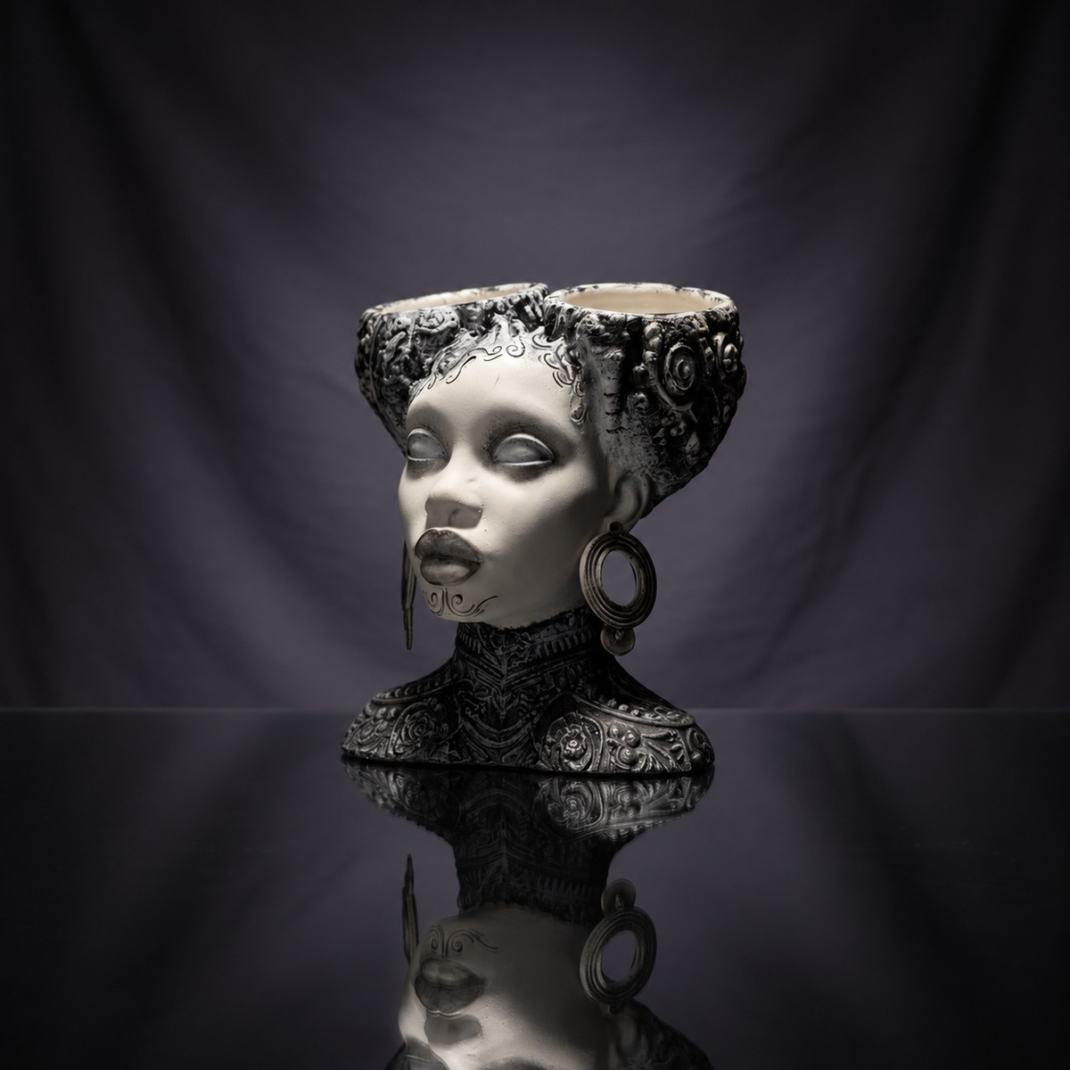 Gothic twin bowl head planter on a black reflective surface with draped fabric