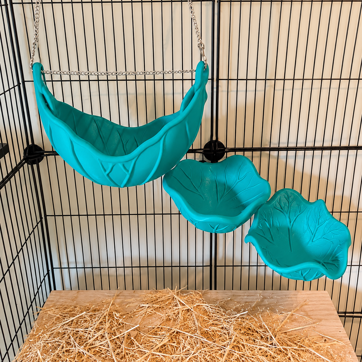 An elevated view of the empty leaf hammock and two different green shelves mounted in a cage.