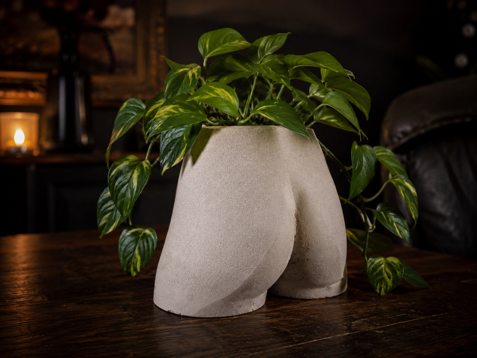 Side lifestyle view of Cheeky Bum cast stone planter in a warm dark room