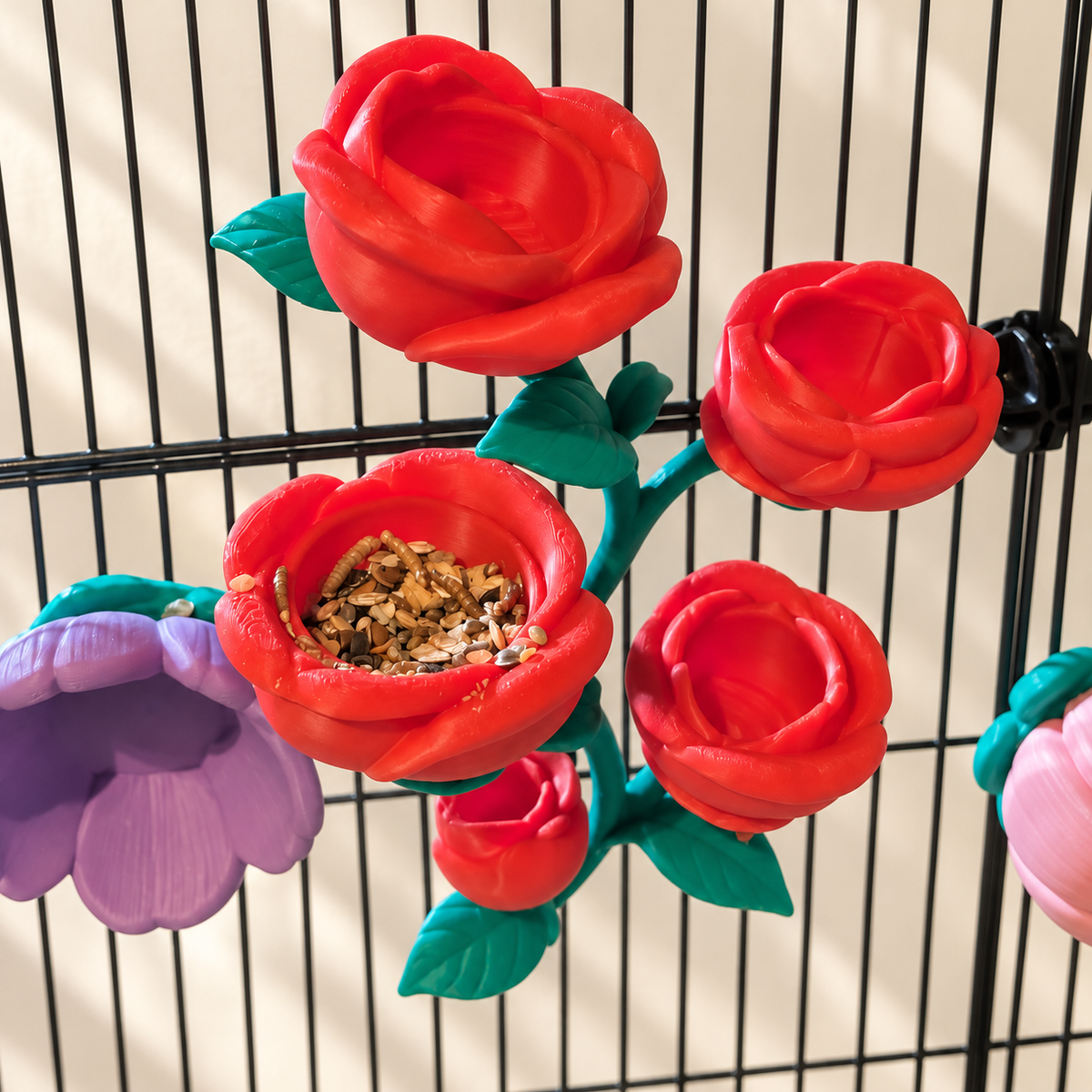 High-angle view of the five-bloom red rose vine with food in a bowl and its connected teal stem visible.