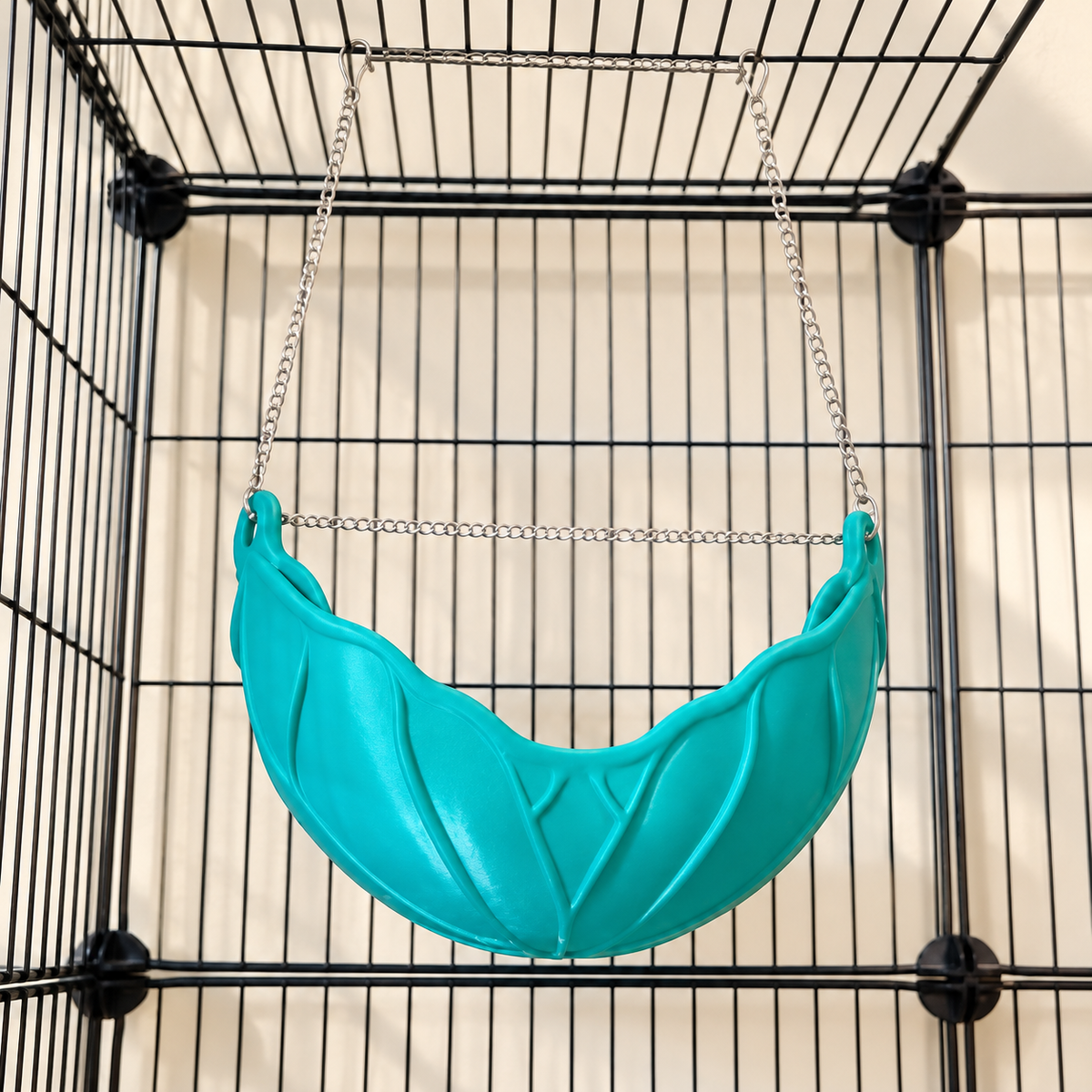 Low-angle view of the leaf hammock and silver hanging chain and clips attached to the cage roof.