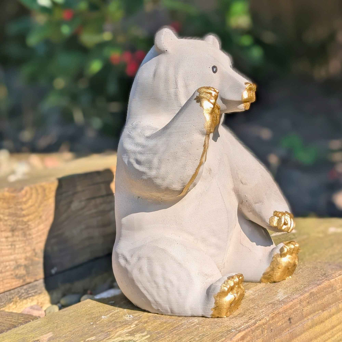 Honey bear garden ornament close view outdoors on a wooden bench