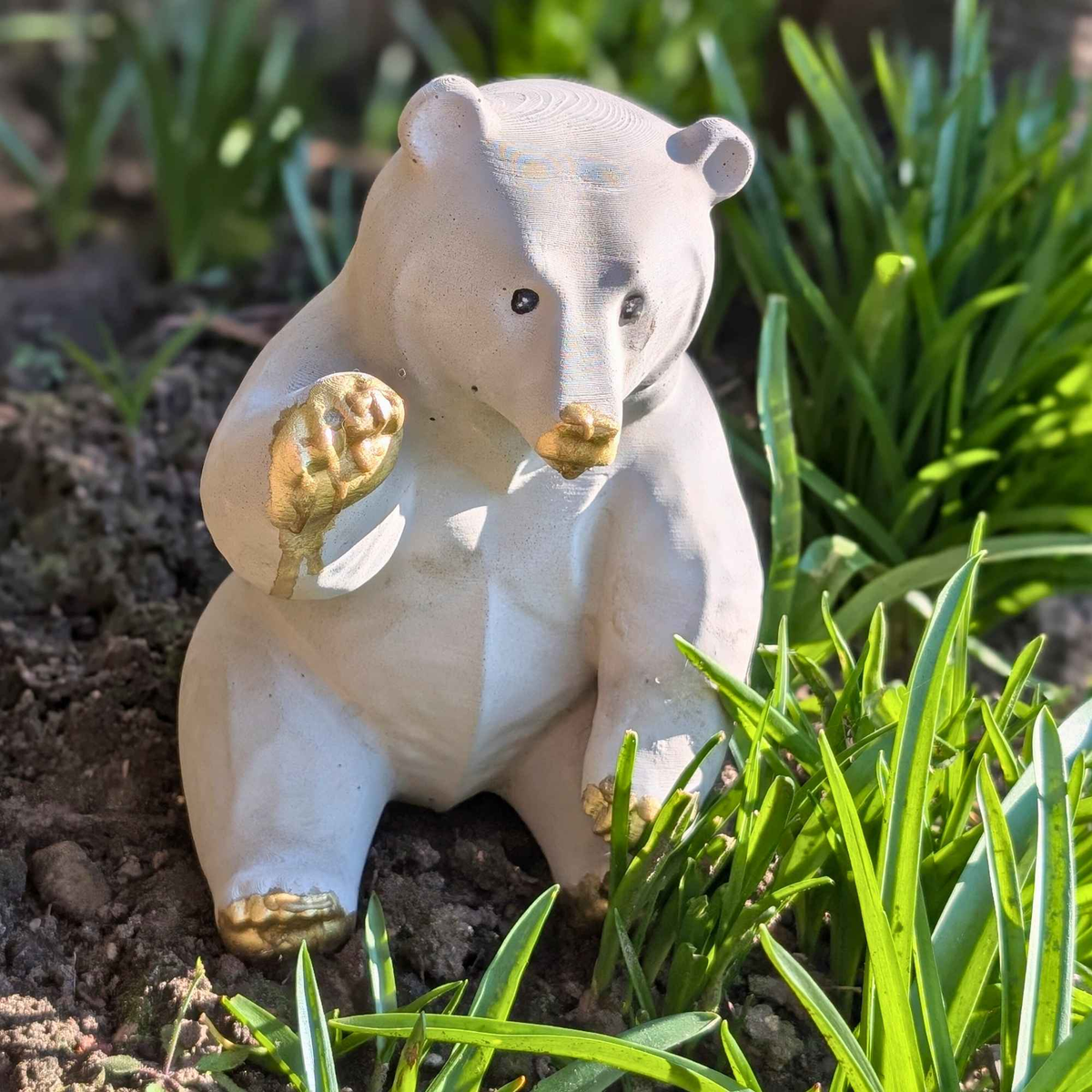 Honey bear garden ornament displayed among green plants outdoors