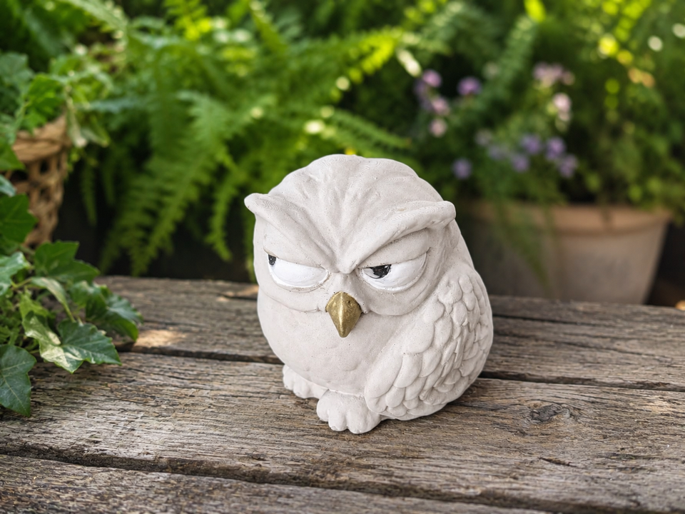 Three-quarter view of The Little Critic cast stone owl sculpture on a rustic garden bench