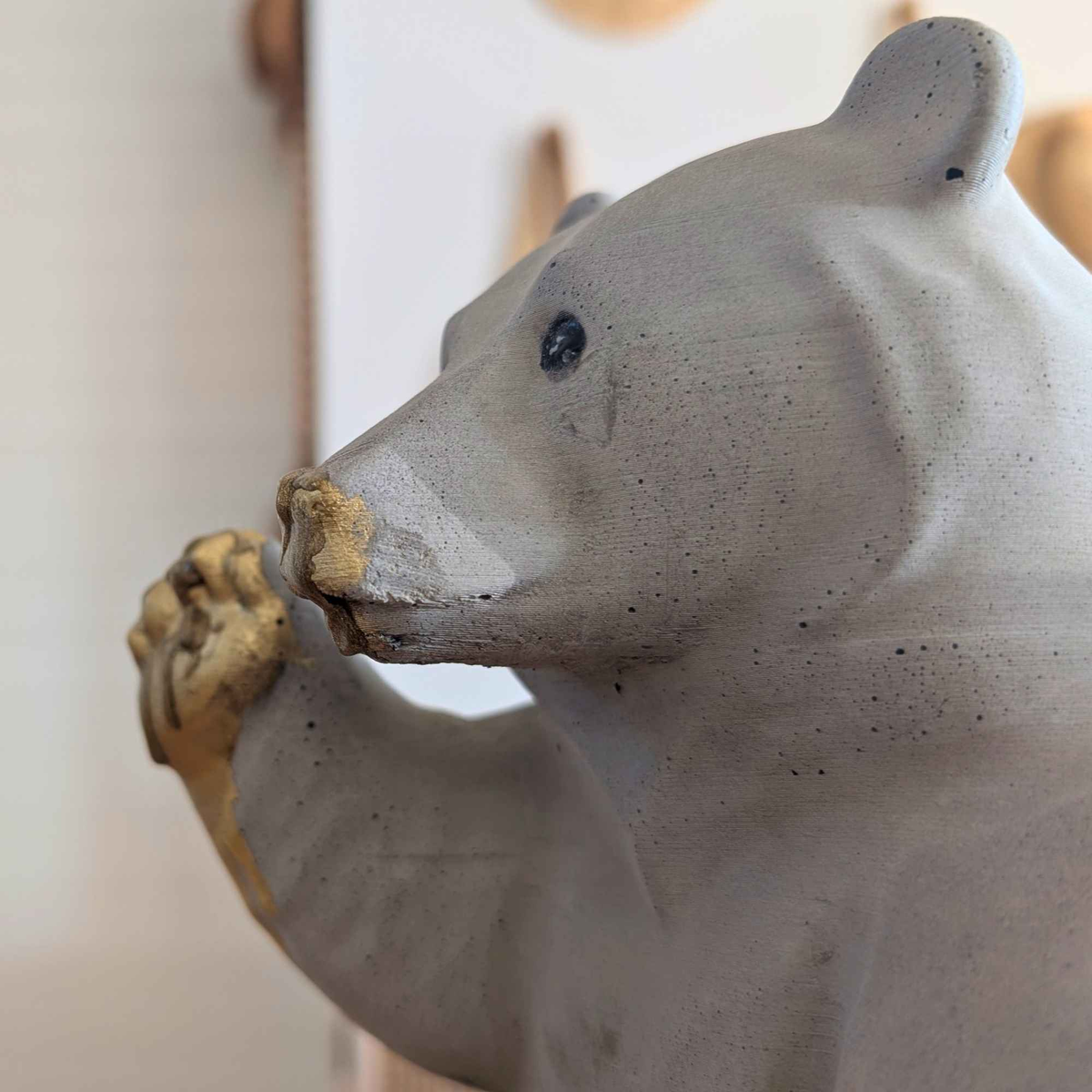 Side close-up of honey bear ornament showing raised paw and cast stone surface