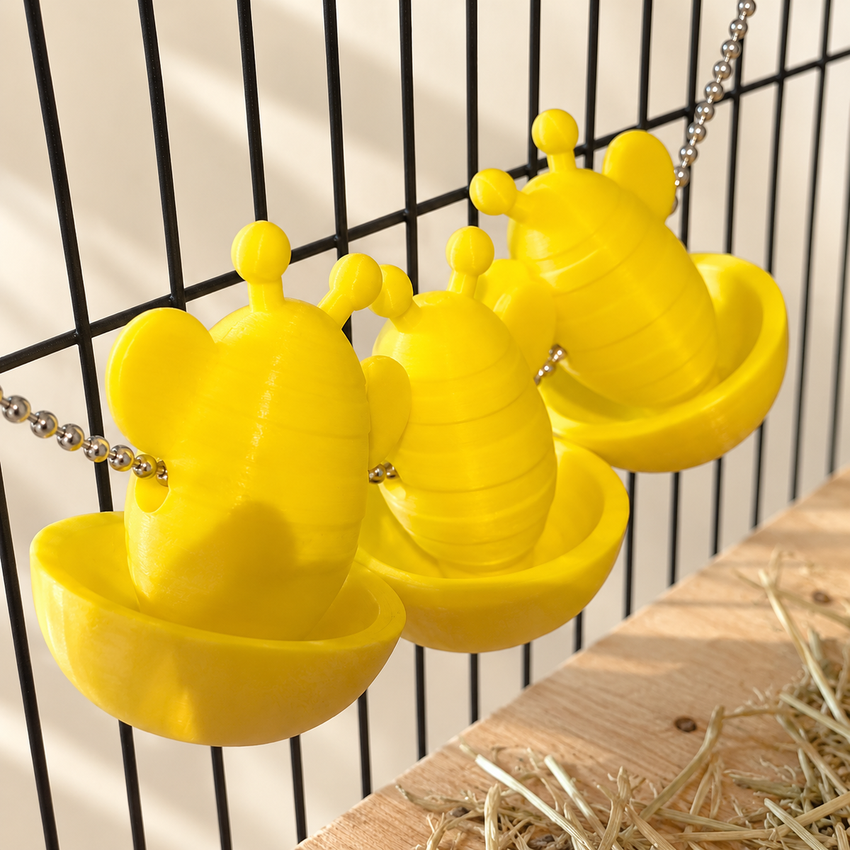 Angled close view of three empty yellow bee cups and the chain passing through their sides.
