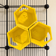 Three yellow hexagonal honeycomb rat shelves arranged on cage bars, with bee relief and side openings visible.
