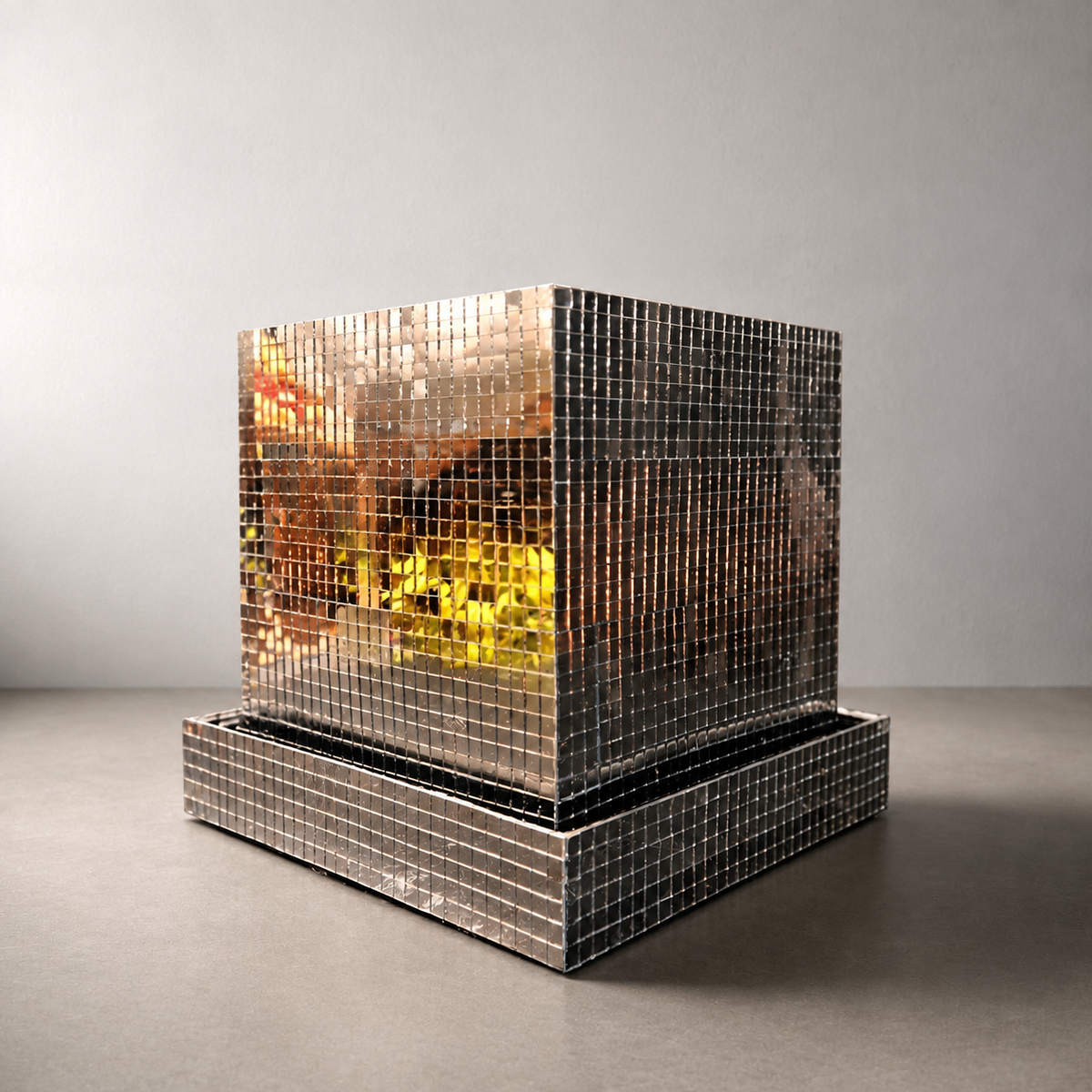 Mirror tile disco cube planter with square drainage tray on a warm-grey tabletop