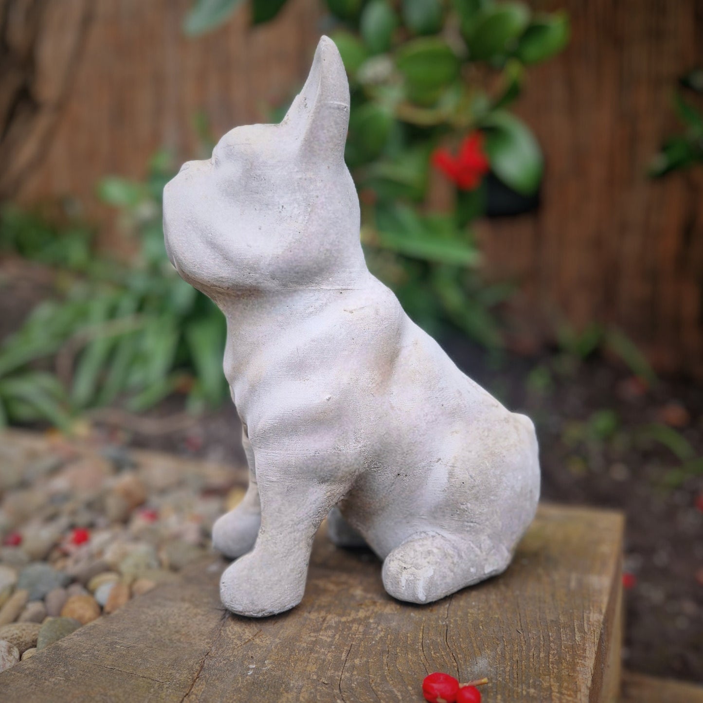 a statue of a white dog sitting on a wooden bench 