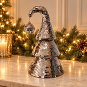 Mirror-ball Christmas tree with hanging bauble on an ivory surface with warm festive lights