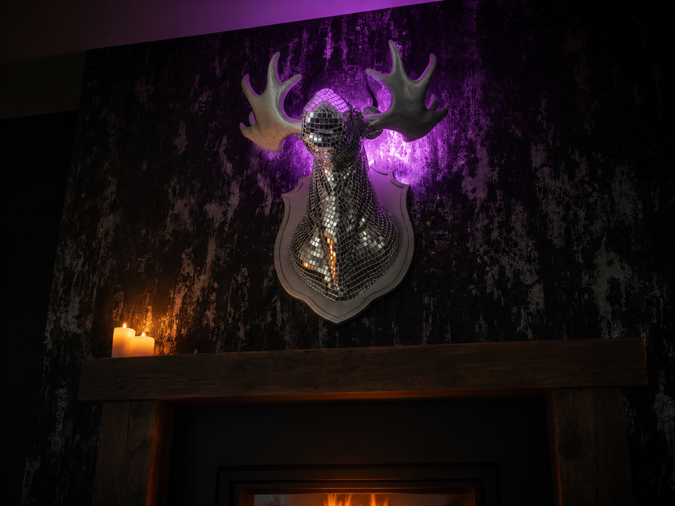 Mirrorball Moose wall art displayed above a dark fireplace mantel