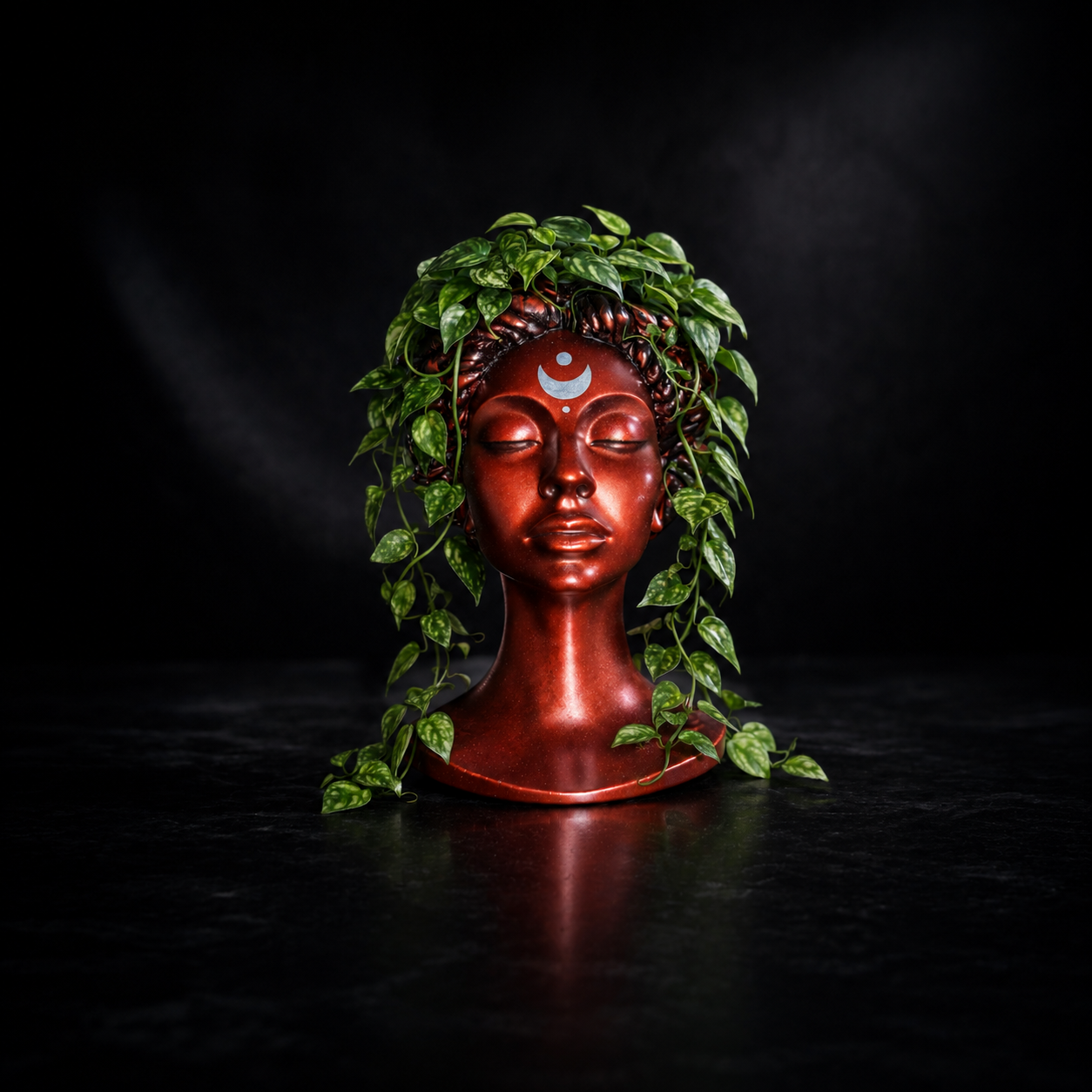 Blood Moon Goddess bust planter with trailing green pothos on a dark background