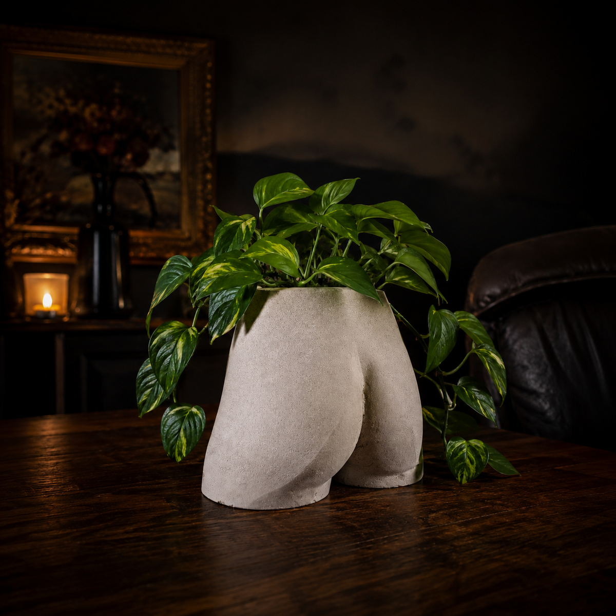 Side lifestyle view of Cheeky Bum cast stone planter in a warm dark room