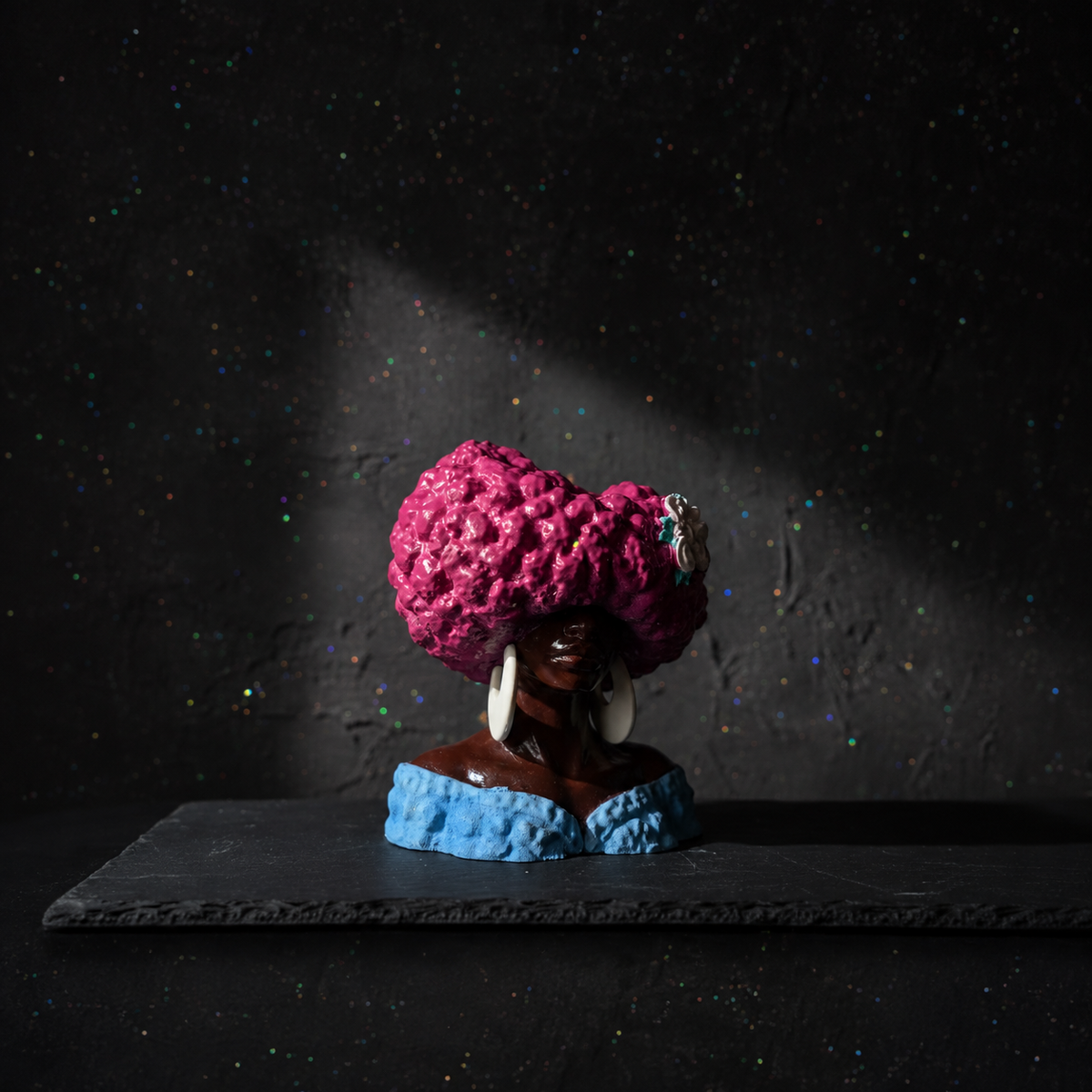 Unplanted Girl Juice head planter on a dark surface with pink textured hair and blue base