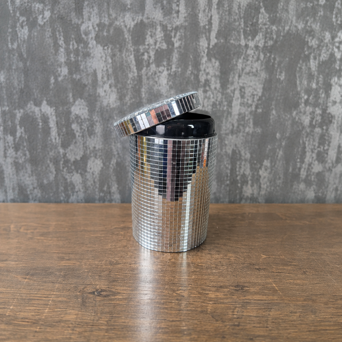 Open silver mirror canister with its hinged lid raised