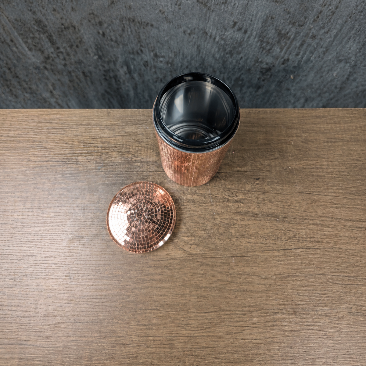 Top view of an open rose gold mirror canister with detached lid