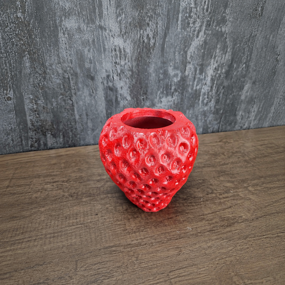 Unplanted red strawberry-shaped planter shown front-on