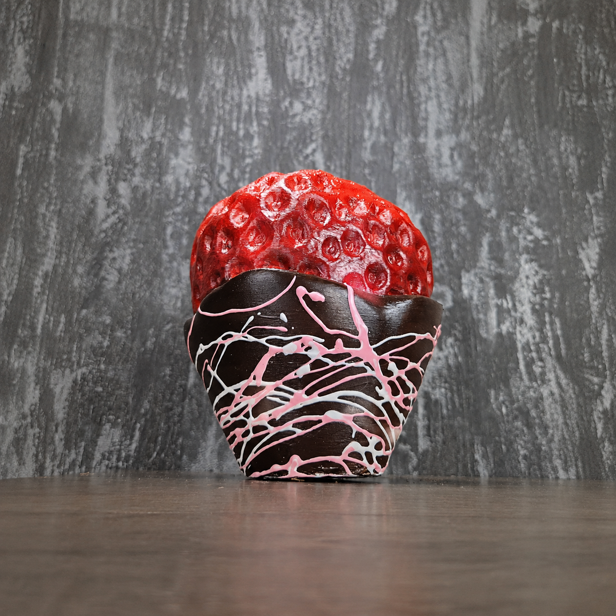Chocolate-dipped strawberry planter with pink drizzle, planted with a spider plant