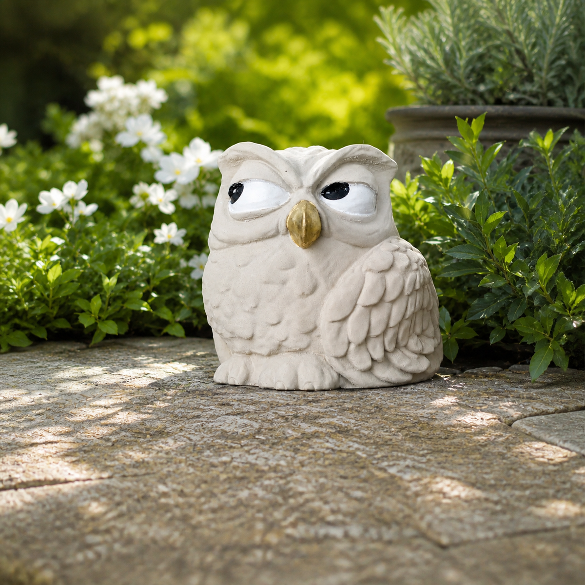 Front view of The Little Critic owl ornament with hand-painted eyes and gold beak in a garden setting