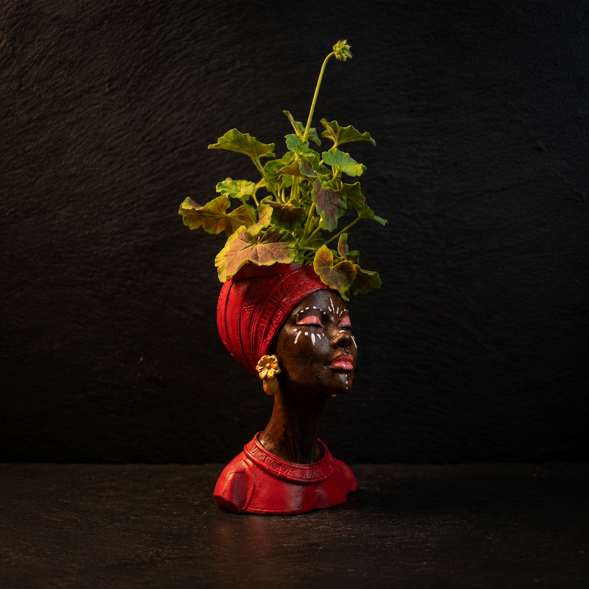 Red Afro woman head planter with gold earrings and pink geraniums