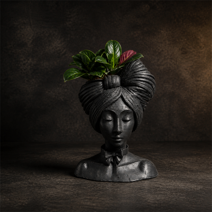 Matte black woman head planter with a green houseplant