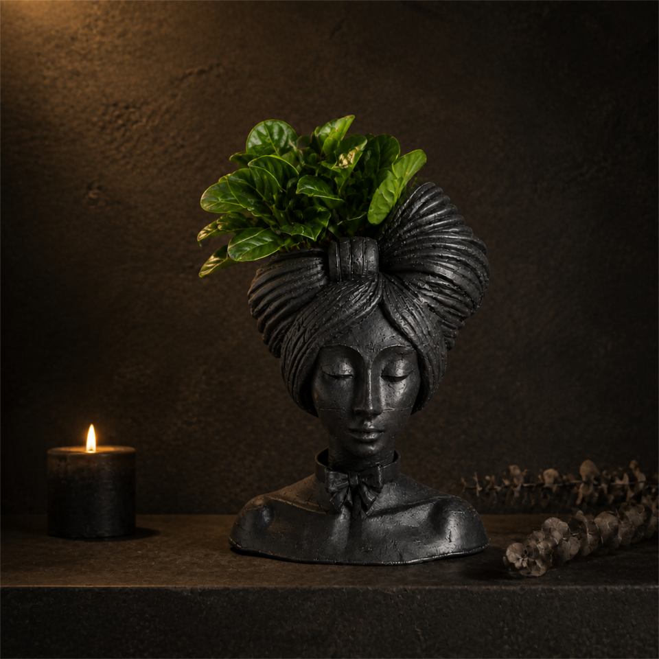 Matte black woman head planter styled on a shelf with a candle